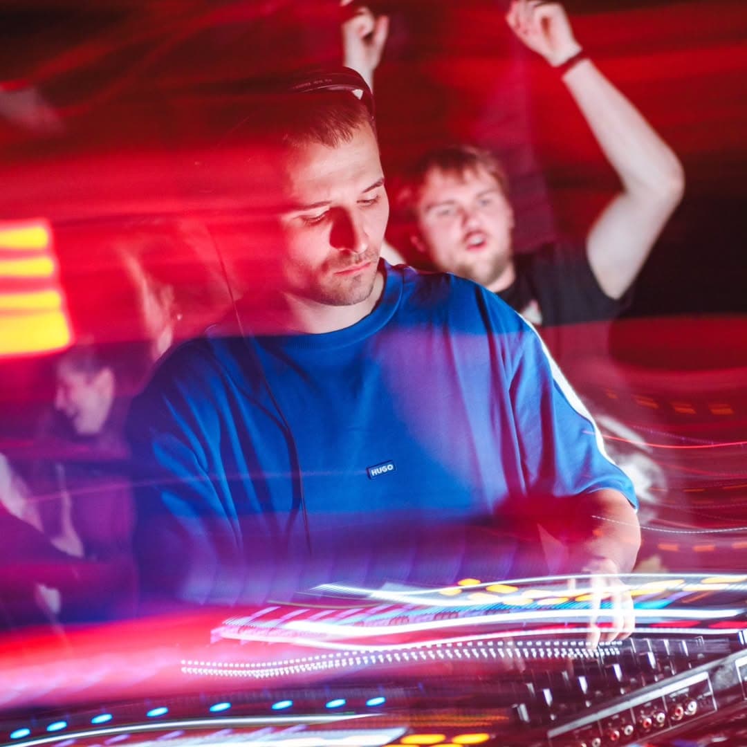 DJ BrajenIRL za mixážním pultem na hlavní stage pod červeno-modrými světly